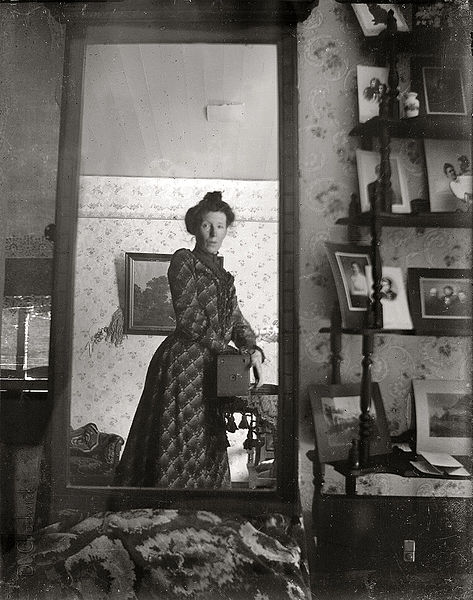 Unidentified woman taking her own photograph using a mirror and a box camera, roughly 1900