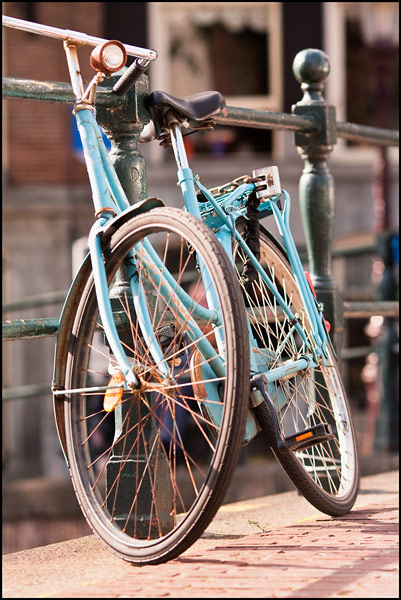 Blauwe omafiets geparkeerd bij gracht