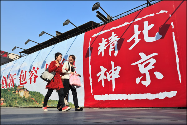 Two Chinese girls walk in front of billboard