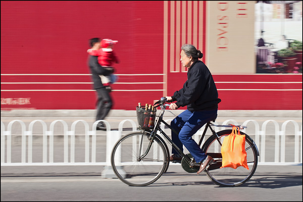 Oude Chinese dame op fiets met rode achtergrond