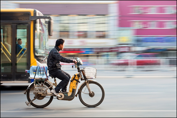 Jongen op e-bike met bus op achtergrond