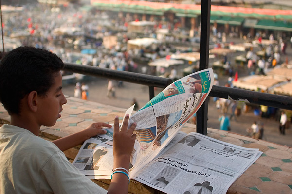 Krantlezende jongen met uitzicht over Place Jemaa el Fna